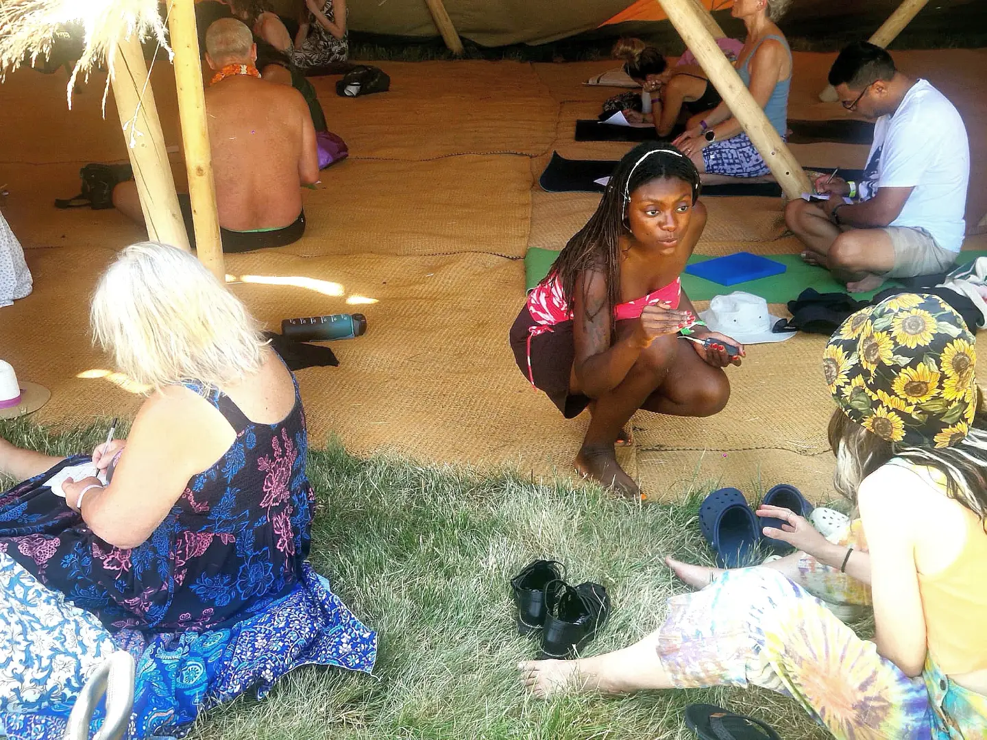 Tanica talking with workshop participants as they write in notebooks inside the Oh Shala festival tent